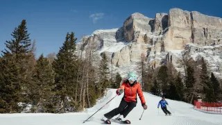 Skiers enjoying a thrilling descent through the snowy slopes of Alta Badia