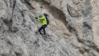 Climber on a Dolomites via ferrata, attached to the lifeline cable on an exposed ridge