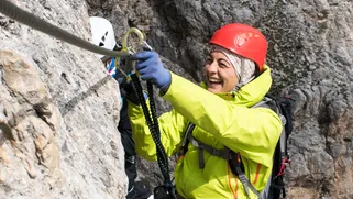 Woman climbing on a via ferrata in the Italian Alps - Dolomites