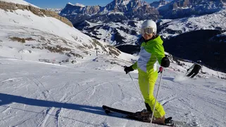 Smiling skier carving down a groomed piste in the Dolomites, Italian Alps.