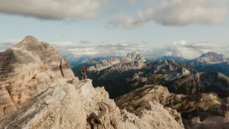 Hiker admiring a sweeping mountain view in the Dolomites, Italian Alps. Photo: Alex Moling