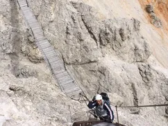 Climber ascending a via ferrata ladder in the Dolomites, Italy – a mix of challenge, safety, and stunning alpine scenery